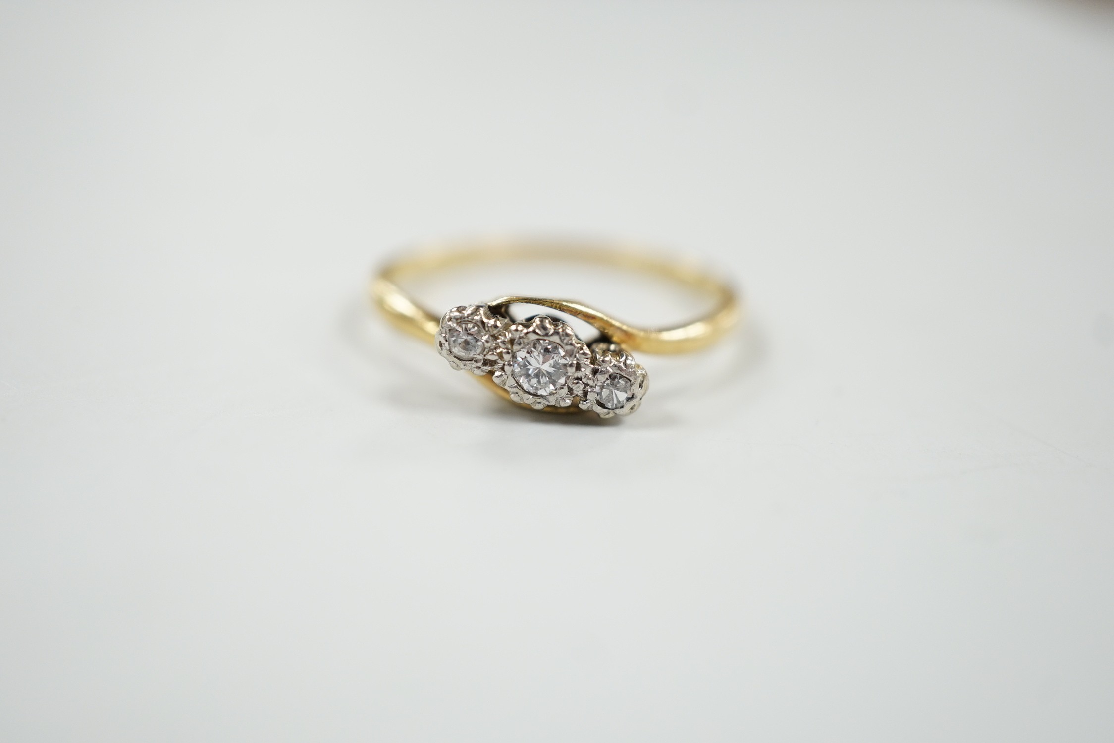 An 18ct & plat, three stone diamond set crossover ring, size T/U, gross weight 3.3 grams.